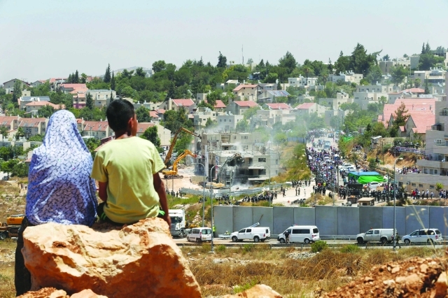 الصورة : طفل فلسطيني ووالدته يشاهدان العملية من منطقة مطلة على مستوطنة «بيت إيل»  |   رويترز