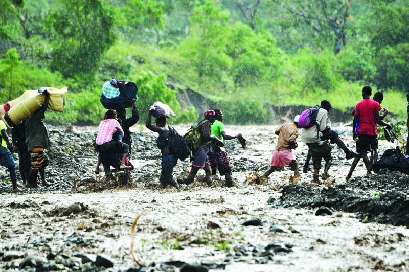 الصورة : TOPSHOT - Haitian people cross the river La Digue in Petit Goave where the bridge collapsed during the rains of the Hurricane Matthew, southwest of Port-au-Prince, October 5, 2016. Haiti and the eastern tip of Cuba -- blasted by Matthew on October 4, 2016 -- began the messy and probably grim task of assessing the storm's toll. Matthew hit them as a Category Four hurricane but has since been downgraded to three, on a scale of five, by the US National Hurricane Center. / AFP / HECTOR RETAMAL