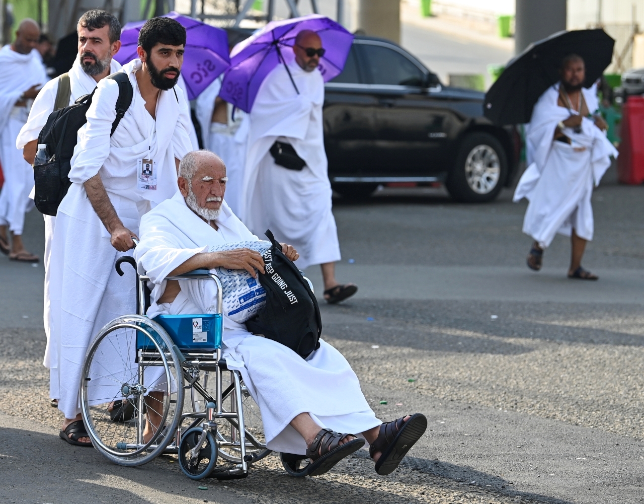 الصورة : حاج مسن يؤدي المناسك على كرسي متحرك | أ ف ب