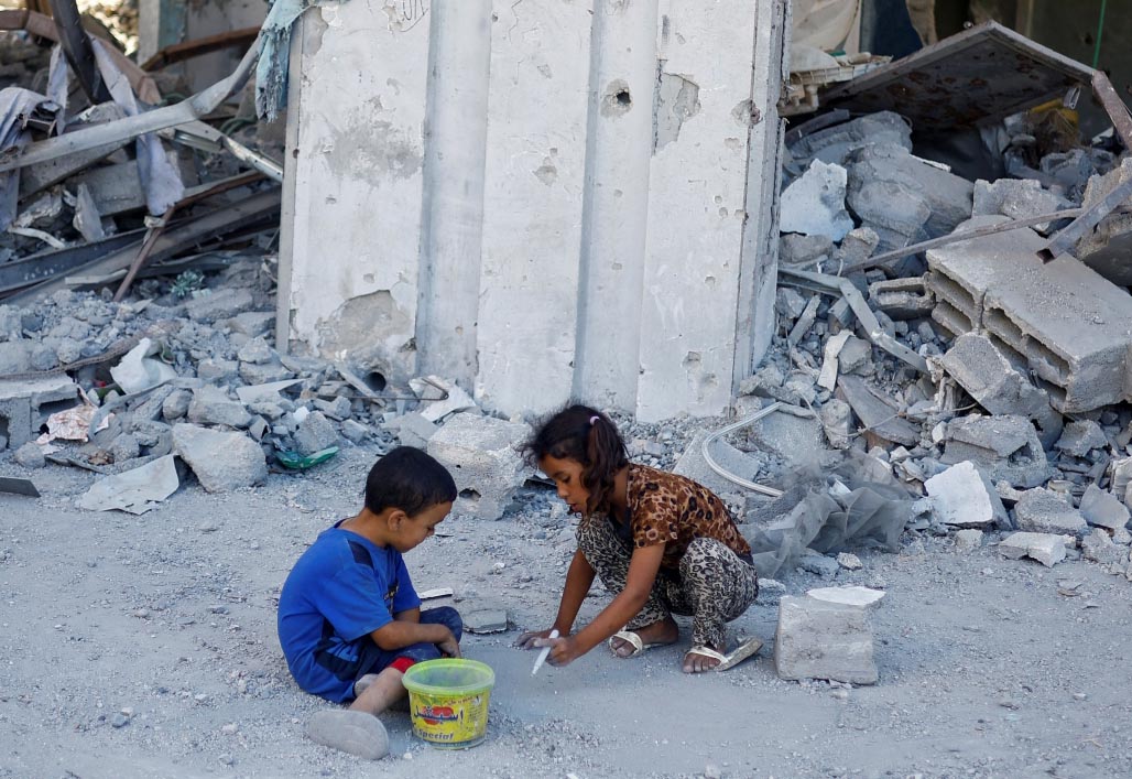 الصورة : طفلان فلسطينيان يلعبان خارج أنقاض منزل دمرته الغارات الإسرائيلية في خان يونس | رويترز